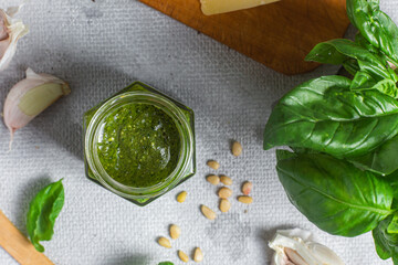 Wall Mural - Pesto sauce in a glass jar on the table. Basil