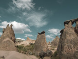 Fototapeta Sawanna - The shot of fairy chimneys, distinctive geological formations, captured against the backdrop of a blue sky adorned with cirrus and cumulus clouds. Landscape photograph.