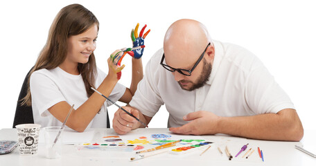 Wall Mural - Painting concept. Schoolgirl painting with father during therapy at home with his tutor with learning and having fun together.