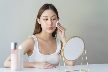 Wall Mural - Close-up view woman using toner and cotton pad to remove makeup