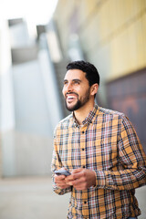 Wall Mural - Handsome young arab man walking outside with mobile phone