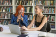 © fizkes - Happy hipster fresh students with trendy hairs sitting at laptop in library, talking, laughing, working on creative ideas for school project together, enjoying education, studentship