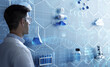 © Paulista - Chemist next to futuristic wall screen equipped with three-dimensional models of pills, atoms and lab tools. Pharmaceutical research concept.