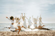 © Prostock-studio - Happy young ladies jumping on sand beach, raising hands up and smiling, enjoying time together on coastline, copy space
