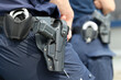  Kajdanki i pistolet w pokrowcu na pasie policjanta. 