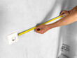 Hand holding measuring tool for apartment wall measurement