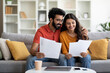 © Prostock-studio - Happy young indian couple checking documents at home,