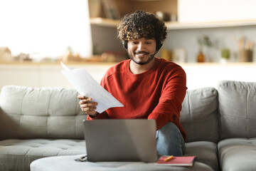 Poster - Indian Freelancer Man In Headset Working With Papers And Laptop At Home