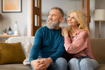 Wall Mural - Mature Couple Enjoying Domestic Comfort Embracing On Sofa At Home