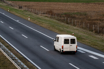 Wall Mural - White delivery van on the highway. White modern delivery small shipment cargo courier van moving fast on motorway road to city urban suburb. The world's best transport of goods.