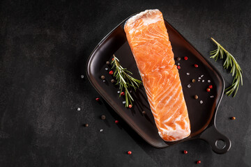 Fresh raw salmon fillet with ingredients for preparation.