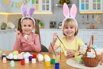 Canvas Print - Children painting Easter eggs at table in kitchen