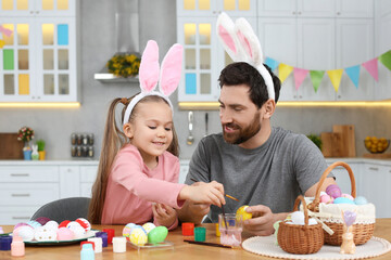 Sticker - Father and his cute daughter painting Easter eggs at table in kitchen