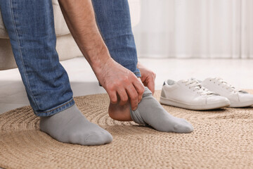 Man putting on grey socks at home, closeup