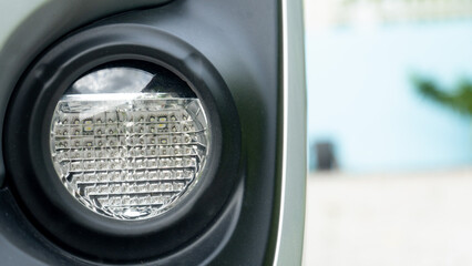 Wall Mural - Front view of round fog lamp of car. and blurred outdoor blue wall.