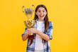 © be free - shocked teen girl accept award on background. proud teen girl with champion cup award. teen girl hold her award champion cup isolated on yellow. teen girl receive award in studio