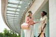 © DragonImages - Stylish young women standing at shopping mall entrance and discussing news