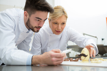 apprentice and confectioner working in chocolate factory