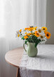 © okkijan2010 - Garden daisies in a ceramic jug on a round wooden table in the living room