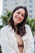 © Jose Calsina - Vertical individual portrait of young adult woman smiling and looking at camera with white tooth standing outdoors. Front view of happy teenage girl with positive expression. Cheerful lady laughing