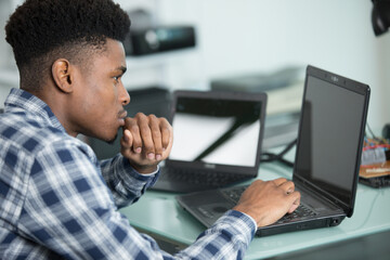 young technician in a workshop with several laptops