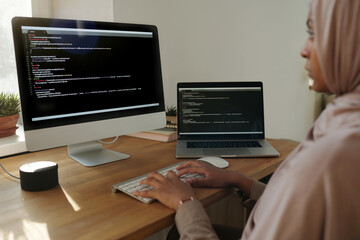 Leinwandbilder - Focus on hands of young Muslim female programmer decoding data or developing new software while sitting in front of computer screen