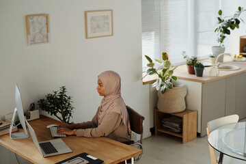 Aufkleber - Serious Muslim female IT manager in hijab sitting by desk in front of desktop computer monitor and decoding data or organizing work