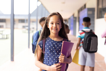 Wall Mural - Portrait of smiling cacuasian schoolgirl in elementary school corridor, with copy space