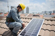 © DragonImages - Worker in uniform and hardhat screwing solar panel on roof