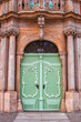 Antique wooden light green doors on city street, front view. Vintage painted double door, victorian style