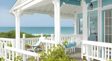 A Quaint Beach House With A Wrap-around Porch And A View Of The Ocean