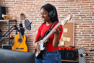 Sticker - Young african american woman artist singing song playing electrical guitar at music studio