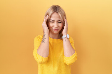 Poster - Young caucasian woman wearing yellow sweater with hand on head, headache because stress. suffering migraine.