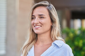 Wall Mural - Young blonde woman smiling confident looking to the side at street