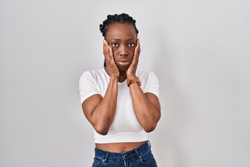 Wall Mural - Beautiful black woman standing over isolated background tired hands covering face, depression and sadness, upset and irritated for problem