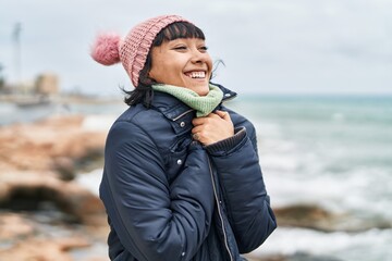 Wall Mural - Young beautiful hispanic woman smiling confident standing at seaside