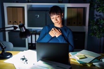 Sticker - Young beautiful woman working at the office at night smiling with hands on chest with closed eyes and grateful gesture on face. health concept.