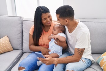 Poster - Hispanic family using smartphone sitting on sofa at home