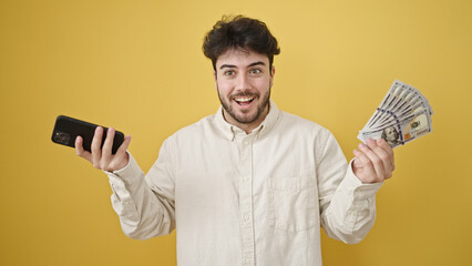 Poster - Young hispanic man smiling holding dollars and smartphone over isolated yellow background