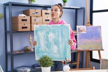 Sticker - Young hispanic girl holding canvas making fish face with mouth and squinting eyes, crazy and comical.