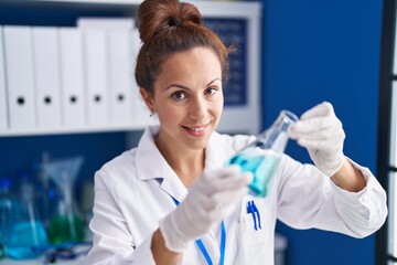 Poster - Young woman scientist measuring liquid working at laboratory