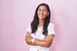 © Krakenimages.com - Young hispanic woman standing over pink background happy face smiling with crossed arms looking at the camera. positive person.
