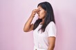 © Krakenimages.com - Young hispanic woman standing over pink background tired rubbing nose and eyes feeling fatigue and headache. stress and frustration concept.