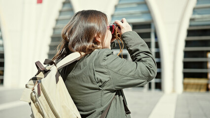 Sticker - Mature hispanic woman with grey hair tourist wearing backpack taking pictures with vintage camera at street