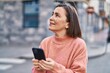 © Krakenimages.com - Middle age woman smiling confident using smartphone at street