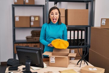 Sticker - Middle age hispanic woman working at small business ecommerce preparing order celebrating crazy and amazed for success with open eyes screaming excited.