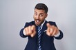 © Krakenimages.com - Handsome hispanic man wearing suit and tie pointing to you and the camera with fingers, smiling positive and cheerful