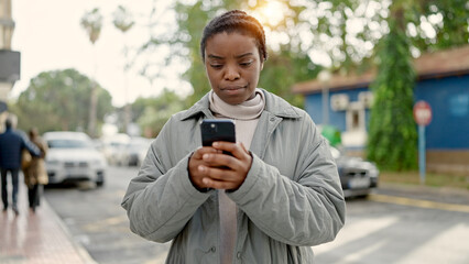 Poster - African american woman using smartphone with serious expression at street