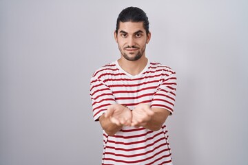 Sticker - Hispanic man with long hair standing over isolated background smiling with hands palms together receiving or giving gesture. hold and protection