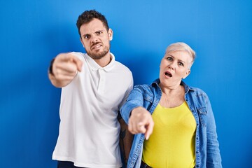 Poster - Young brazilian mother and son standing over blue background pointing displeased and frustrated to the camera, angry and furious with you